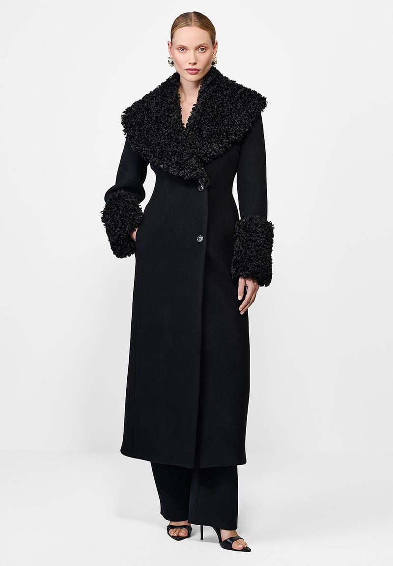 Czarny płaszcz z dużym, teksturowanym kołnierzem i mankietami, o prostym kroju, z zapięciem na guziki oraz luksusowym wykończeniem tkaniny.