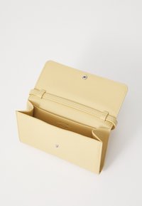 Cartera de cuero amarilla con textura suave, cierre a presión y un interior que cuenta con múltiples compartimentos para tarjetas y efectivo.