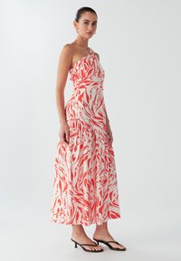 Ühe õlaga kihiline maksikleit pehmest kangast, millel on korallide ja kreemika abstraktne muster. Voolav disain koos vormiva vöökohaga.