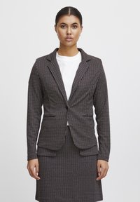 Črno-bela črtasta blazer jakna z oprijetim krojem, z nazobčanimi klapnicami, dolgimi rokavi, dvema sprednjima žepoma in enojnim gumbom za zapiranje.