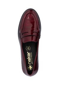 Mocassin en cuir verni bordeaux avec semelle noire, bandeau à monnaie et logo doré "Rieker Antistress" à l'intérieur.