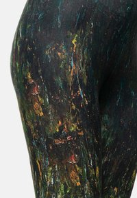 Zwarte leggings met een getextureerd abstract patroon, waarin groene, oranje en blauwe spatten zijn verwerkt, wat een gemarmerde uitstraling geeft. Strakke pasvorm.