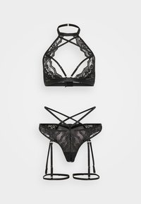 Sort blondeundertøjsæt med halter-bh med krydsede stropper og matchende trusse med strømpeholderstropper og guldfarvede hardware-detaljer.