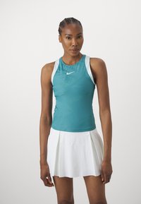 Teal sportieve tanktop met een netstructuur en witte accenten, gecombineerd met een geplooide witte rok, die een strakke pasvorm heeft geschikt voor sport.