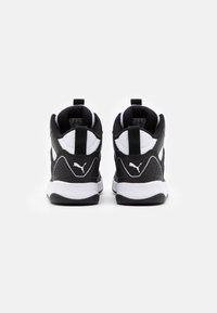 Černobílé sportovní boty s vysokým designem, texturovaným černým svrškem, bílými akcenty a logem na patě.