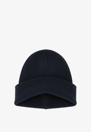 Bonnet tricoté en bleu marine foncé. Il présente une texture côtelée, un revers pliable et un petit patch logo sur le côté.