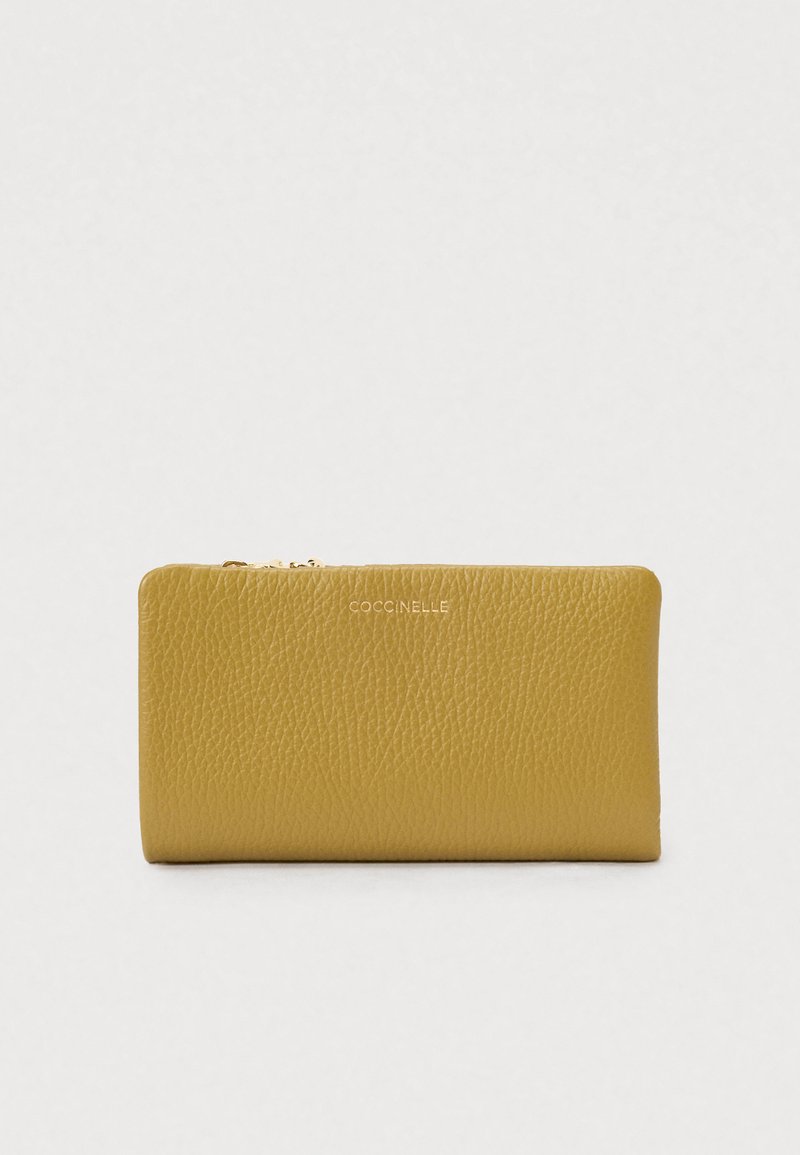 Portofel galben din piele texturată, cu fermoar auriu și numele mărcii "Coccinelle" embosat în centru pe față.