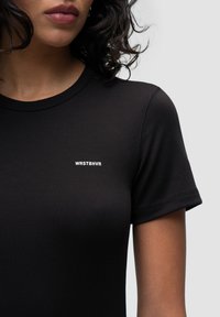 Czarny t-shirt z krótkim rękawem wykonany z gładkiego materiału, z białym logo "WRSTBVR" na lewej piersi. Czysty design z dopasowanym krojem.