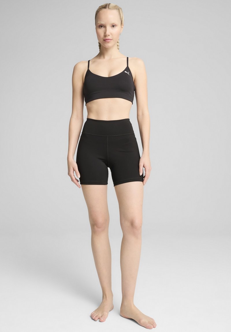 Reggiseno sportivo nero con spalline sottili e pantaloni corti. Tessuto liscio ed elastico; design a vita alta; senza motivi o accenti visibili.