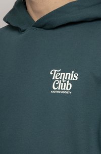Tyrkysová mikina s kapucňou a sťahovacou šnúrkou, so bielym logom "Tennis Club" a textom "KAOTIKO SOCIETY" v modernom písme. Viditeľná jemná štruktúra látky.