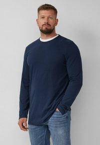 Marineblauwe shirt met lange mouwen en een ronde halslijn, met een contrasterende witte binnenkraag. Zachte stof met minimale rek.