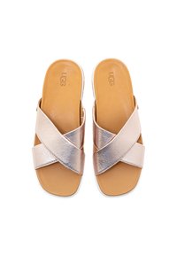 Růžově zlaté platformové sandály s kříženými kovovými pásky, hladkým koženým stélkou a odolnou podrážkou pro stabilitu. Viditelné logo značky.