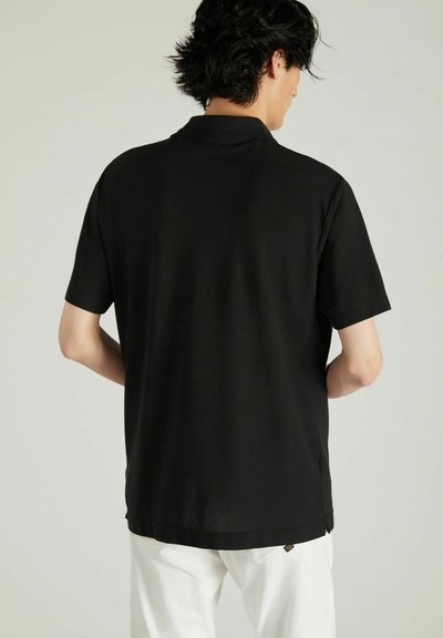 Polo negro de manga corta, color sólido, fabricado en un tejido suave y con un ligero brillo. Presenta un cuello clásico y un diseño de corte relajado.