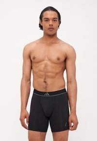 Boxers atléticos pretos com uma cintura elástica, apresentando um logo discreto e um tecido suave e leve, ajustando-se confortavelmente ao corpo.