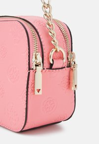 Pink læderhåndtaske med prægede logoer i hjørnet, dobbelte guldrulleslugere og en guld kæde rems vedhæftning mod en hvid baggrund.