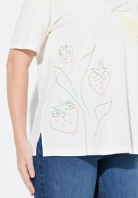 Hvid kortærmet T-shirt med farverige broderede jordbær og et citrondesign. Slidsser i siderne for ekstra detaljer.