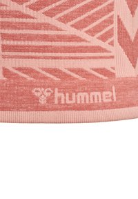 Rosa sportkläder med ett texturerat mönster som har diagonala ränder. Logotypen "hummel" i en ljusare nyans är framträdande.
