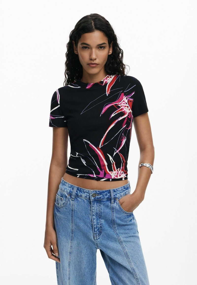 Top corto a maniche corte in maglia nera con stampa floreale colorata in rosa, rosso e bianco. Abbinato a jeans in denim azzurro chiaro a vita alta.