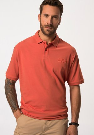 Korallenfarbendes Poloshirt mit einer Knopfleiste mit drei Knöpfen, kurzen Ärmeln und gesticktem Logo. Besteht aus einem weichen, strukturierten Baumwollstoff.