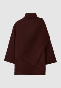 Burgunderfarbener Wollmantel mit hohem Kragen, asymmetrisch drapierter Paneele und weiten Ärmeln. Textilstruktur mit weicher Oberfläche, entworfen für eine lockere Passform.