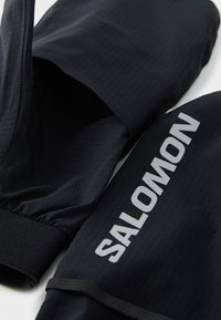 Crne trkačke rukavice od mekanog materijala, s elastičnim manžetama i istaknutim bijelim logotipom "SALOMON" sa strane.