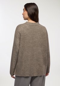Pullover color taupe con scollo rotondo, morbido al tatto e dal taglio morbido. La parte posteriore presenta un orlo a coste e spalle leggermente scese.