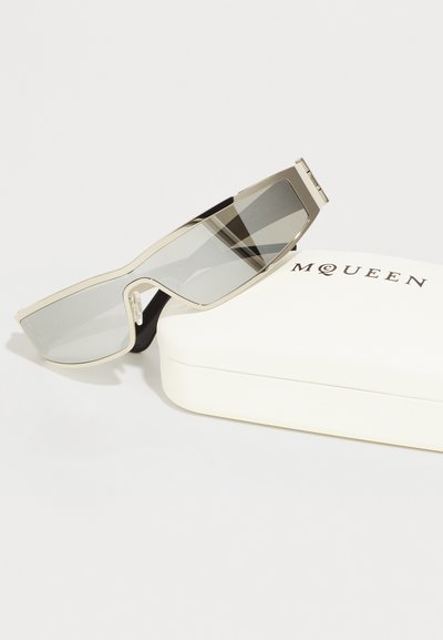 Silberne Sonnenbrille mit rechteckigen, grauen Gläsern. Enthält ein weißes Etui mit der Aufschrift "MQUEEN" in schwarzer Schrift.