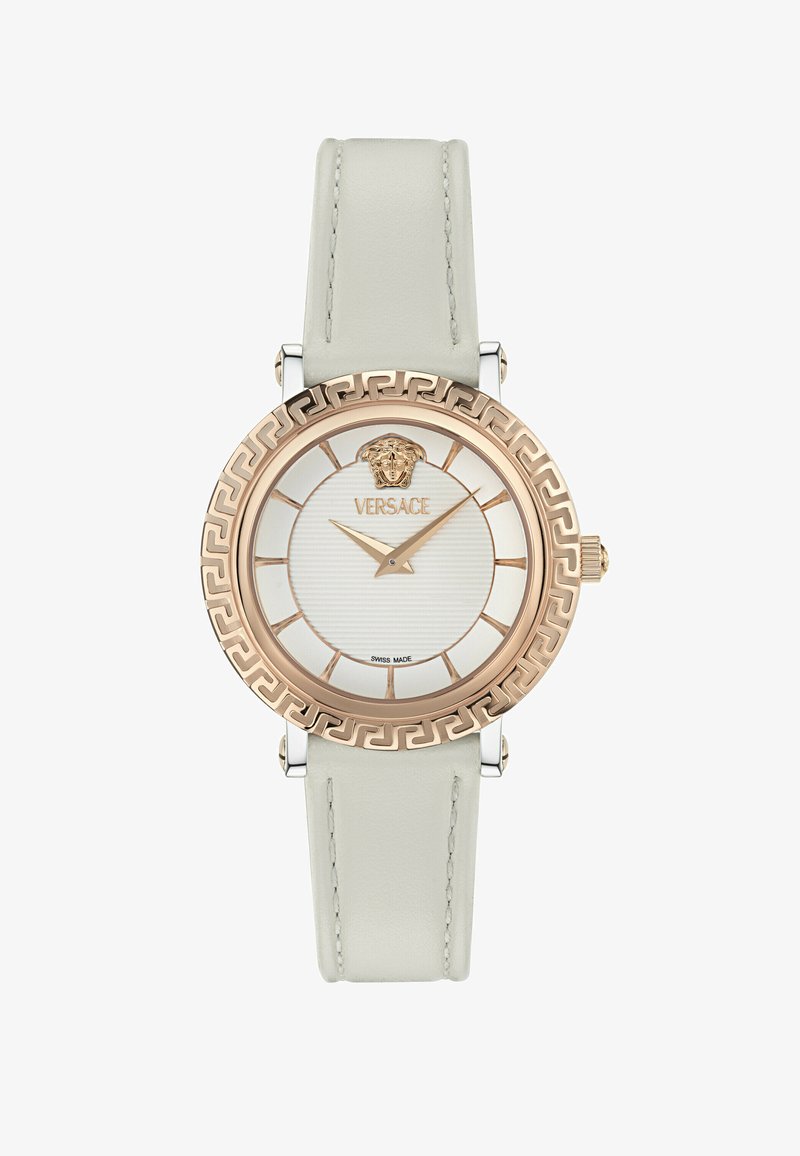 Apvalus „Versace“ riešo laikrodis su baltos odos dirželiu, rožinio aukso bezeliu su graikiško rakto raštu ir baltu ciferblatu su auksiniu Medūzos logotipu ir rodyklėmis.