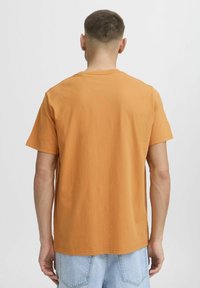 Orange bomulds T-shirt med korte ærmer, rund hals og en afslappet pasform. Stoffet har en glat tekstur uden synlige mønstre eller detaljer.
