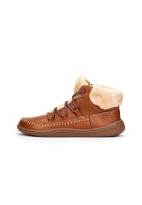 Botas de tobillo de cuero marrón con un cuello de piel sintética, diseño de cordones y costuras en contraste. La suela es de color marrón claro con un acabado texturizado.