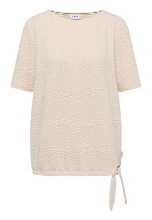 Beigen värinen lyhythihainen teksturoitu pusero pyöreällä pääntiellä ja solmittavalla yksityiskohdalla alaosan oikeassa reunassa.