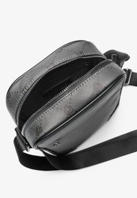 Black crossbody bag with a textured exterior and printed pattern. Features a zip closure and an adjustable strap. Smooth interior lining.
