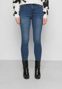 Tunna blå denimjeans med en slät textur och minimalt blekning, i kombination med svarta eleganta ankelstövlar med spetsig tå.