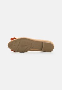 Talpa de pantof din suede bej cu un design texturat, având un accent de fundiță roșie pe spate. Marimea 37 imprimată pe laterale.