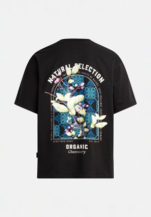 Camiseta de algodón negra con un gráfico floral colorido en la parte posterior que incluye texto, enmarcado por un diseño geométrico azul y el logo de la marca debajo.