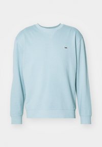 Jasnoniebieska bluza wykonana z miękkiego materiału, z klasycznym okrągłym dekoltem, ściągaczami przy rękawach oraz małym haftowanym logo na piersi.