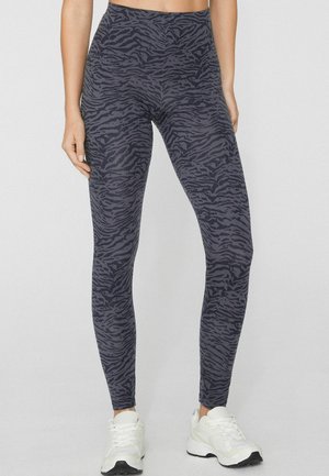 Leggings taille haute en gris foncé avec un motif à rayures zèbre. Confectionnées en tissu extensible, avec une texture lisse et une coupe ajustée.