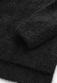 Tissu texturé noir avec une surface duveteuse, affichant un tissage doux et dense, plié pour montrer son épaisseur et sa sensation luxueuse.