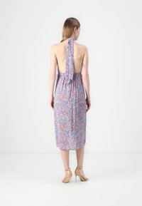Halterneck-Kleid mit offener Rückseite, das ein florales Muster in lila und orange Tönen aufweist, aus leichtem Stoff gefertigt.