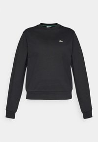 Sweat-shirt noir à manches longues col rond, avec poignets et ourlet côtelés, arborant un petit logo crocodile vert sur la poitrine gauche.