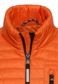 Pomarańczowy pikowany kołnierz kurtki z czarnym zamkiem błyskawicznym częściowo zapięty, z widoczną pętlą materiału wewnątrz okolicy szyi.