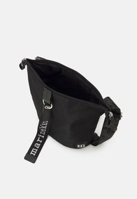 Black nylon bag with a zip closure, adjustable strap featuring "marimekko" text, and a simple design. Interior is unadorned.