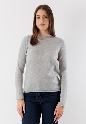 Maglione grigio lavorato a maglia con maniche lunghe, scollo rotondo e texture morbida. Abbinato a jeans in denim blu scuro. Design minimalista.
