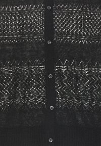 Svart stickad cardigan med ett strukturerat öppet stickat mönster, fem knappar fram och ribbad nederkant och ärmslut.