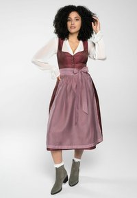 Robe traditionnelle avec un corsage bordeaux et un motif à pois, une jupe rose pâle, et un nœud. Complétée par des bottines grises à la cheville.