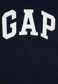 Marineblå bomullssweatshirt med fet hvit "GAP"-skrift i blokkstil over brystet. Glatt tekstur, design med rund hals.