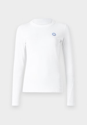Langermet hvit skjorte laget av myk stoff med rund hals og et lite blått smilendes ansikt brodert på venstre bryst.
