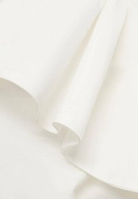Tissu blanc drapé en douces courbes, texture lisse avec un léger éclat, affichant des bords délicats et un jeu de lumière subtil.