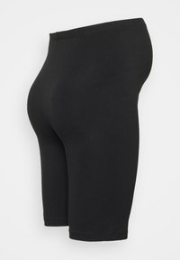Leggings noirs jusqu'aux genoux en tissu lisse et extensible. Dotés d'une taille haute et d'une silhouette ajustée.
