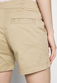 Shorts kaki avec une poche arrière, dotés d'un ourlet soigné et de détails de couture. Confectionnés en tissu léger, conçus pour le confort.